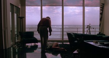 Movie still from “Sleeping with the Enemy” (1991), directed by Joseph Ruben – A man and a woman in front of a large window; Wide shot, Over the shoulder angle