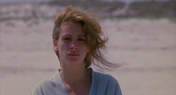 Movie still from “Sleeping with the Enemy” (1991), directed by Joseph Ruben – A young woman with long blonde hair standing on the beach; Close Up shot, Low angle
