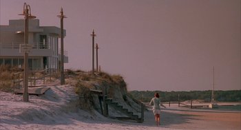 Movie still from “Sleeping with the Enemy” (1991), directed by Joseph Ruben – A woman walking down a beach path near stairs; Extreme Wide shot, Low angle