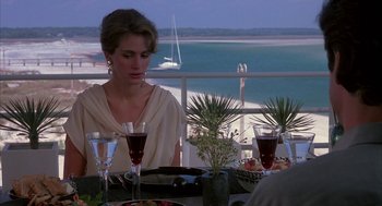 Movie still from “Sleeping with the Enemy” (1991), directed by Joseph Ruben – A woman sitting at a table with a plate of food; Medium shot, Over the shoulder angle