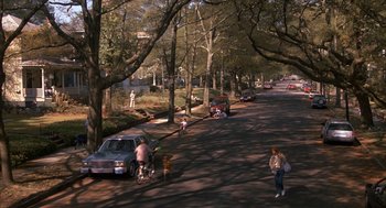 Movie still from “Sleeping with the Enemy” (1991), directed by Joseph Ruben – A street scene with cars parked on the side of the road; Extreme Wide shot, High angle