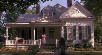 Movie still from “Sleeping with the Enemy” (1991), directed by Joseph Ruben – A woman standing on the steps of an old house; Wide shot, Low angle