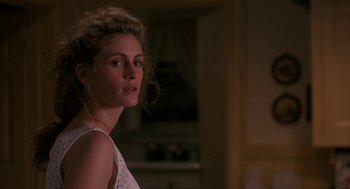 Movie still from “Sleeping with the Enemy” (1991), directed by Joseph Ruben – A woman in a white top is standing in a room; Close Up shot, Over the shoulder angle