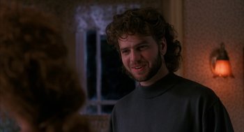 Movie still from “Sleeping with the Enemy” (1991), directed by Joseph Ruben – A man with curly hair is smiling for the camera; Close Up shot, Over the shoulder angle