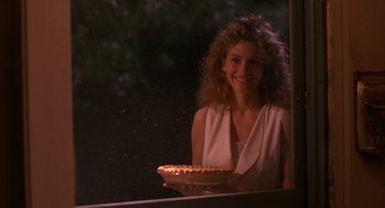 Movie still from “Sleeping with the Enemy” (1991), directed by Joseph Ruben – A woman holding a plate of food in front of a window; Close Up shot, Over the shoulder angle