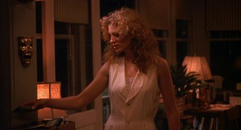 Movie still from “Sleeping with the Enemy” (1991), directed by Joseph Ruben – A woman standing in a room holding a lamp; Medium shot, Over the shoulder angle