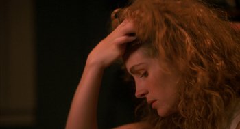 Movie still from “Sleeping with the Enemy” (1991), directed by Joseph Ruben – A woman with long red hair holding her hand to her head; Close Up shot, Over the shoulder angle