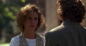 Movie still from “Sleeping with the Enemy” (1991), directed by Joseph Ruben – A woman with curly blonde hair and a floral shirt is looking at a man; Close Up shot, Over the shoulder angle