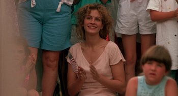 Movie still from “Sleeping with the Enemy” (1991), directed by Joseph Ruben – A woman clapping her hands in front of a group of people; Medium shot, Over the shoulder angle