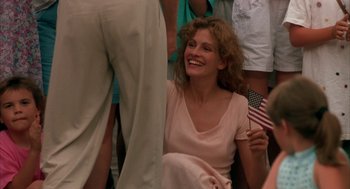 Movie still from “Sleeping with the Enemy” (1991), directed by Joseph Ruben – A woman sitting on the ground holding an american flag; Medium shot, Over the shoulder angle