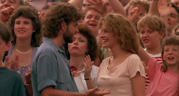 Movie still from “Sleeping with the Enemy” (1991), directed by Joseph Ruben – A man and a woman talking to each other in front of a crowd; Medium shot, Over the shoulder angle