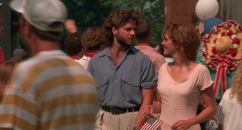 Movie still from “Sleeping with the Enemy” (1991), directed by Joseph Ruben – A man and a woman standing next to each other holding an american flag; Medium shot, Over the shoulder angle