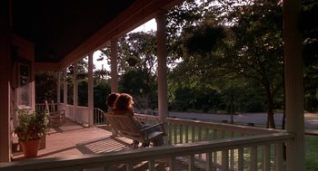 Movie still from “Sleeping with the Enemy” (1991), directed by Joseph Ruben – A woman sitting on a chair on the porch of a house; Wide shot, Low angle