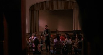 Movie still from “Sleeping with the Enemy” (1991), directed by Joseph Ruben – A man standing in front of a group of people in a room; Wide shot, High angle