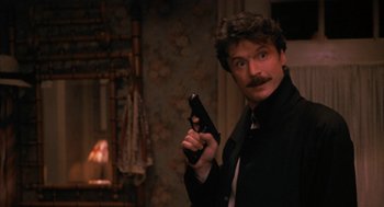Movie still from “Sleeping with the Enemy” (1991), directed by Joseph Ruben – A man holding a gun while wearing a suit and tie; Close Up shot, Low angle