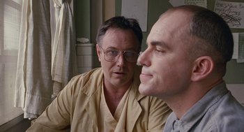 Movie still from “Sling Blade” (1996), directed by Billy Bob Thornton – A man in glasses is looking at another man in glasses; Close Up shot, Low angle