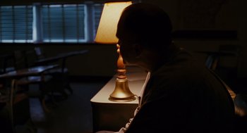 Movie still from “Sling Blade” (1996), directed by Billy Bob Thornton – A man sitting in front of a table with a lamp on top of it; Medium shot, High angle