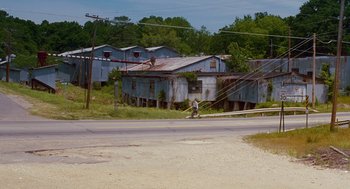 Movie still from “Sling Blade” (1996), directed by Billy Bob Thornton – An old rundown building sits on the side of the road; Extreme Wide shot, Low angle