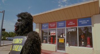 Movie still from “Sling Blade” (1996), directed by Billy Bob Thornton – A dog that is standing in front of a store; Wide shot, Low angle