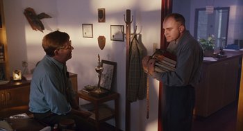 Movie still from “Sling Blade” (1996), directed by Billy Bob Thornton – Two men are standing in a room holding books; Medium shot, Low angle