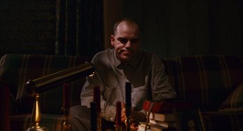 Movie still from “Sling Blade” (1996), directed by Billy Bob Thornton – A man sitting in front of a bunch of candles; Medium shot, Low angle