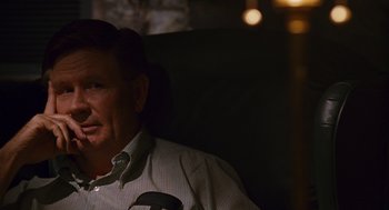 Movie still from “Sling Blade” (1996), directed by Billy Bob Thornton – An older man sitting in a chair in a dark room; Close Up shot, Over the shoulder angle