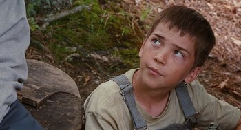 Movie still from “Sling Blade” (1996), directed by Billy Bob Thornton – A young boy sitting on the ground in the woods; Close Up shot, High angle