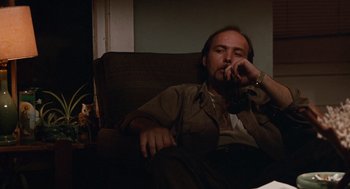 Movie still from “Sling Blade” (1996), directed by Billy Bob Thornton – A man sitting on a couch with his hand on his face; Medium shot, Low angle