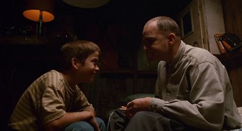 Movie still from “Sling Blade” (1996), directed by Billy Bob Thornton – A man sitting next to a young boy in a room; Medium shot, Low angle