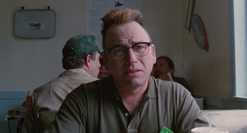 Movie still from “Sling Blade” (1996), directed by Billy Bob Thornton – A person wearing glasses and a brown shirt; Close Up shot, Over the shoulder angle