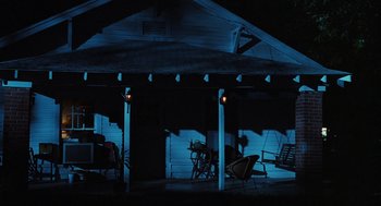 Movie still from “Sling Blade” (1996), directed by Billy Bob Thornton – A porch lit up at night with lights on; Extreme Wide shot, Low angle