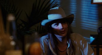 Movie still from “Sling Blade” (1996), directed by Billy Bob Thornton – A woman wearing a cowboy hat sitting in front of a plant; Close Up shot, Over the shoulder angle