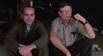 Movie still from “Sling Blade” (1996), directed by Billy Bob Thornton – Two men sitting next to each other and one is smoking a cigarette; Medium shot, Low angle
