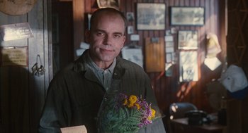 Movie still from “Sling Blade” (1996), directed by Billy Bob Thornton – A man holding a bouquet of flowers in his hand; Medium shot, Over the shoulder angle