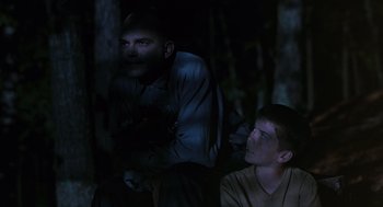 Movie still from “Sling Blade” (1996), directed by Billy Bob Thornton – A man and a boy in the woods at night; Medium shot, Over the shoulder angle