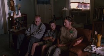 Movie still from “Sling Blade” (1996), directed by Billy Bob Thornton – A man , woman , and a boy sitting on a couch; Medium shot, Over the shoulder angle