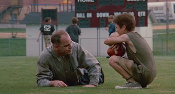Movie still from “Sling Blade” (1996), directed by Billy Bob Thornton – A man and a boy are sitting on the grass; Wide shot, Low angle