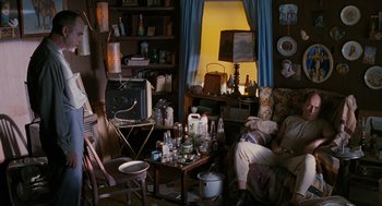 Movie still from “Sling Blade” (1996), directed by Billy Bob Thornton – A living room filled with lots of furniture and clutter; Wide shot, High angle