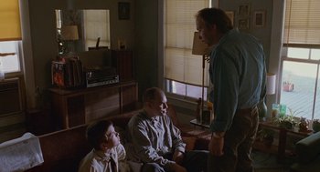 Movie still from “Sling Blade” (1996), directed by Billy Bob Thornton – Two men and a young boy in a living room; Medium shot, Low angle