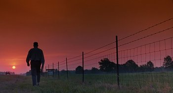 Movie still from “Sling Blade” (1996), directed by Billy Bob Thornton – A man standing in a field next to barbed wire fence; Extreme Wide shot, Low angle