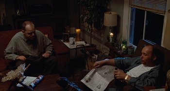 Movie still from “Sling Blade” (1996), directed by Billy Bob Thornton – Two people are sitting at a table with a newspaper; Medium shot, High angle