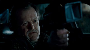 Movie still from “Slither” (2006), directed by James Gunn – An older man holding a gun in a dark room; Close Up shot, Low angle