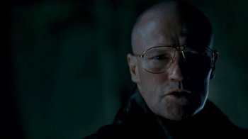 Movie still from “Slither” (2006), directed by James Gunn – A bald man wearing glasses and a black jacket; Close Up shot, Low angle