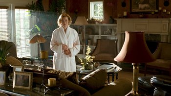 Movie still from “Slither” (2006), directed by James Gunn – A woman in a white robe standing in a living room; Wide shot, Over the shoulder angle