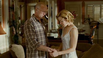 Movie still from “Slither” (2006), directed by James Gunn – A man and a woman holding hands in a living room; Medium shot, Over the shoulder angle