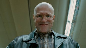 Movie still from “Slither” (2006), directed by James Gunn – A man with a shaved head wearing glasses and a leather jacket; Close Up shot, Low angle