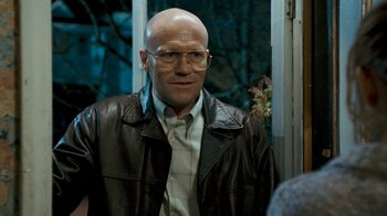 Movie still from “Slither” (2006), directed by James Gunn – A bald man wearing glasses and a leather jacket; Close Up shot, Over the shoulder angle