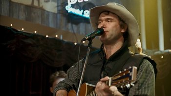 Movie still from “Slither” (2006), directed by James Gunn – A man in a cowboy hat is playing a guitar; Close Up shot, Over the shoulder angle