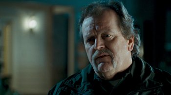 Movie still from “Slither” (2006), directed by James Gunn – An older man with a beard and mustache looking at the camera; Close Up shot, Over the shoulder angle