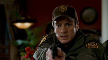 Movie still from “Slither” (2006), directed by James Gunn – A man holding a gun while wearing a hat; Close Up shot, Over the shoulder angle